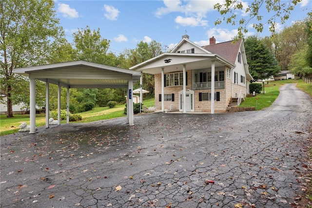 view of front of house featuring covered porch, a carport, and a front lawn