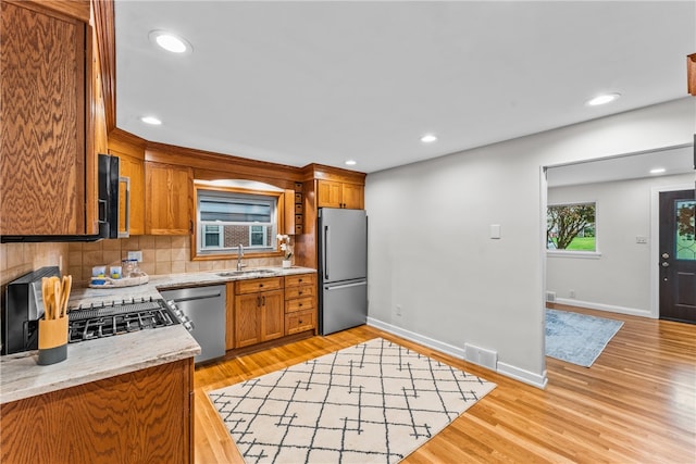 kitchen featuring stainless steel appliances, tasteful backsplash, sink, and light wood-type flooring