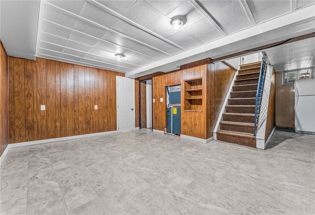 basement featuring wooden walls and white refrigerator