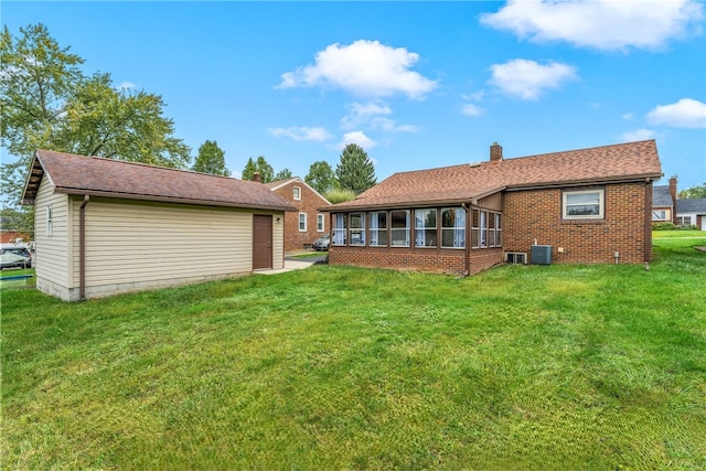 rear view of property featuring a sunroom, central AC, and a lawn