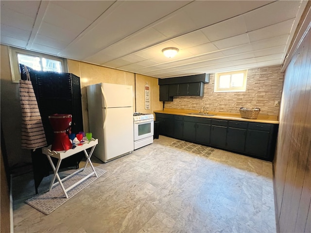 kitchen featuring a wealth of natural light, white appliances, and wood walls