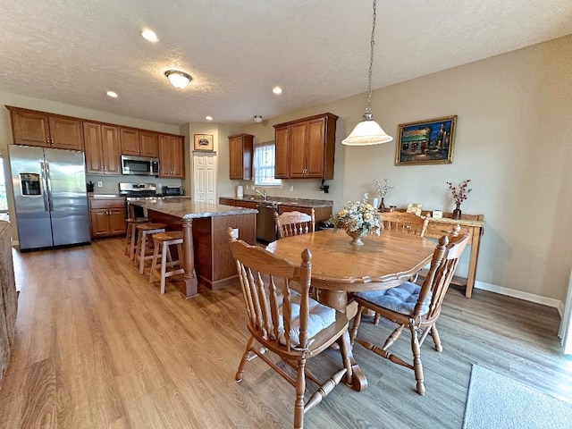 dining room with a textured ceiling and light hardwood / wood-style floors