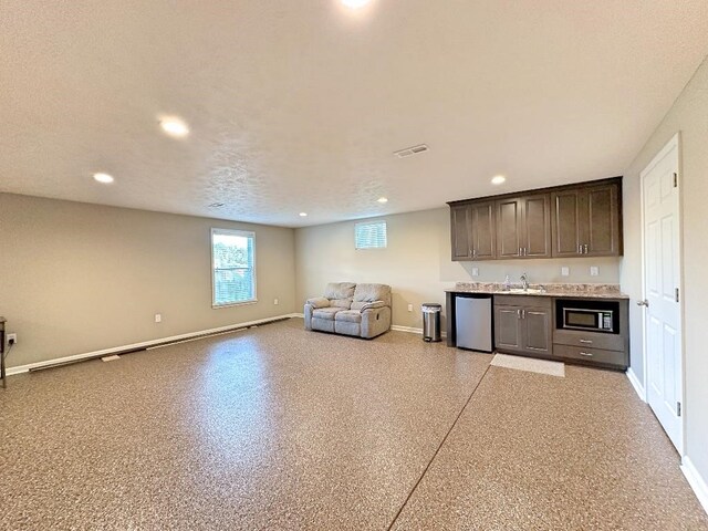 kitchen with dark brown cabinets, stainless steel appliances, a textured ceiling, and sink