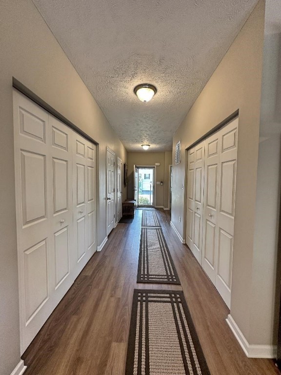 corridor featuring a textured ceiling and dark hardwood / wood-style flooring