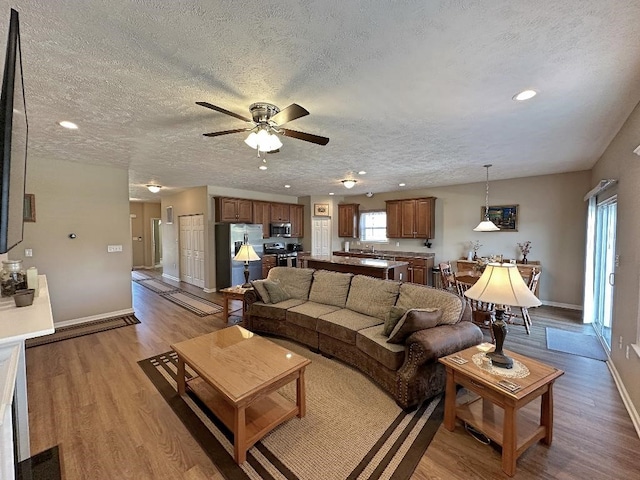 living room featuring a textured ceiling, ceiling fan, and light hardwood / wood-style flooring