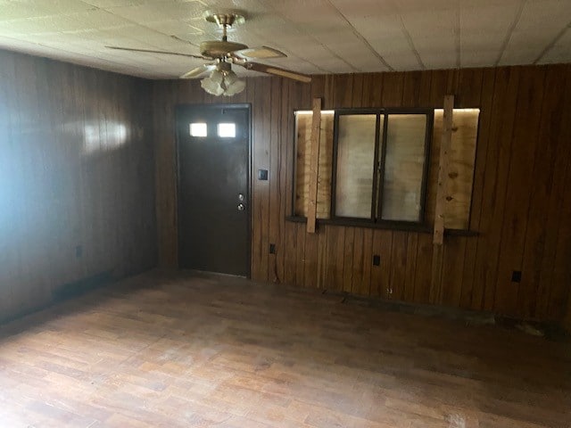 foyer featuring ceiling fan, light hardwood / wood-style flooring, and wooden walls