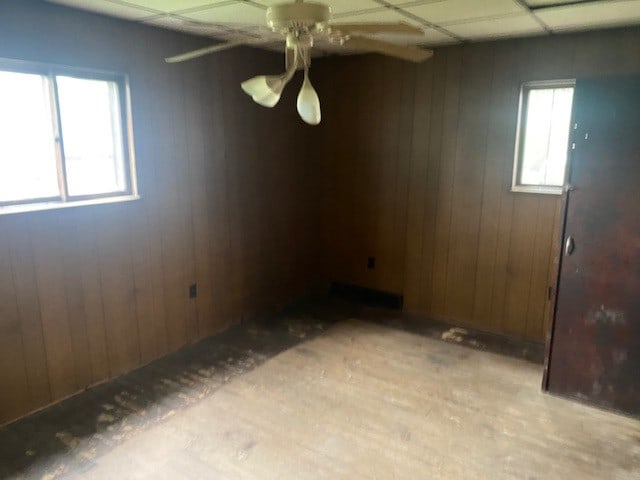 unfurnished room featuring wooden walls and ceiling fan