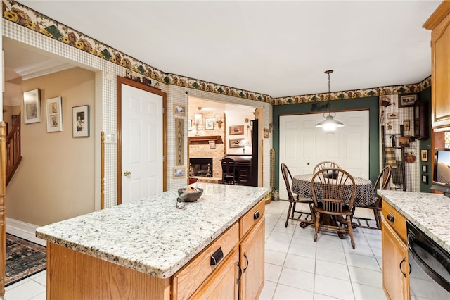 kitchen featuring dishwasher, light stone counters, a kitchen island, a brick fireplace, and decorative light fixtures