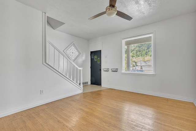 interior space with light wood-type flooring, a textured ceiling, and ceiling fan