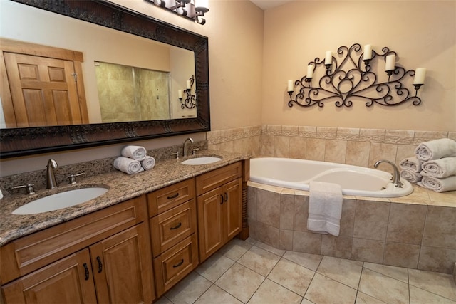 bathroom featuring tile patterned flooring, vanity, and tiled bath