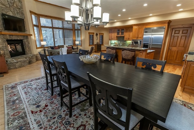 dining space featuring a stone fireplace, a chandelier, and light hardwood / wood-style floors