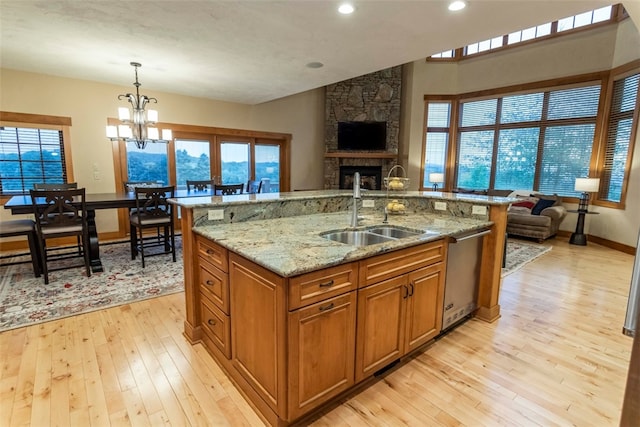 kitchen with pendant lighting, sink, light hardwood / wood-style floors, and a stone fireplace