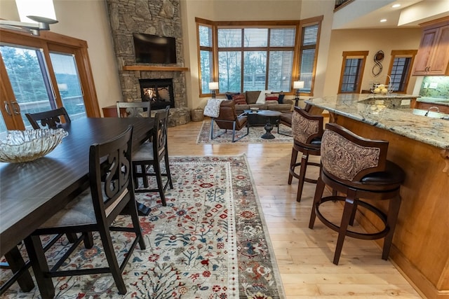 dining area featuring plenty of natural light, a stone fireplace, and light hardwood / wood-style flooring