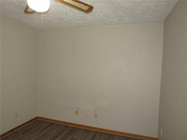 empty room with a textured ceiling and dark hardwood / wood-style floors