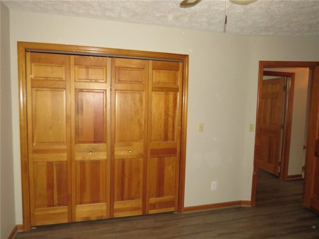 unfurnished bedroom featuring a textured ceiling, dark hardwood / wood-style floors, ceiling fan, and a closet