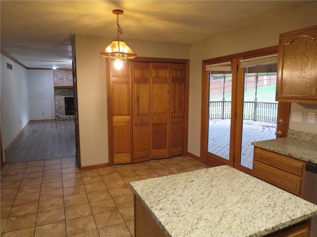 kitchen with light stone counters, ornamental molding, decorative light fixtures, and light tile patterned floors