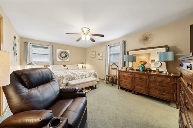 bedroom featuring multiple windows, ceiling fan, and light colored carpet