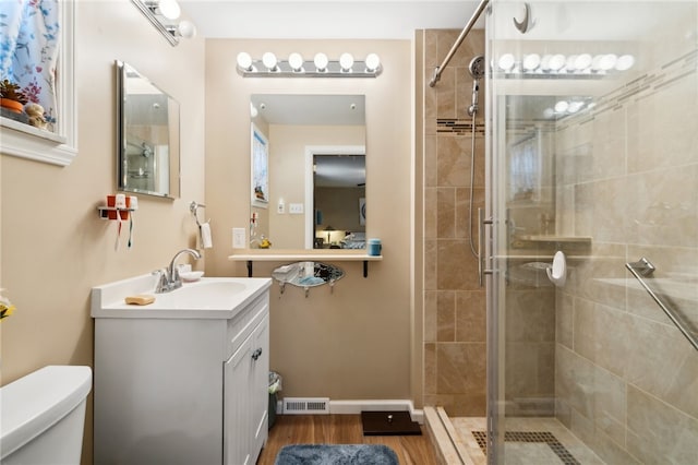 bathroom featuring hardwood / wood-style flooring, vanity, toilet, and an enclosed shower