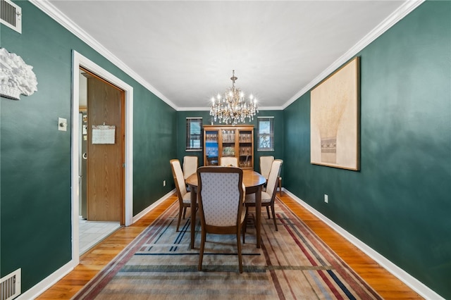 dining space featuring an inviting chandelier, hardwood / wood-style floors, and crown molding