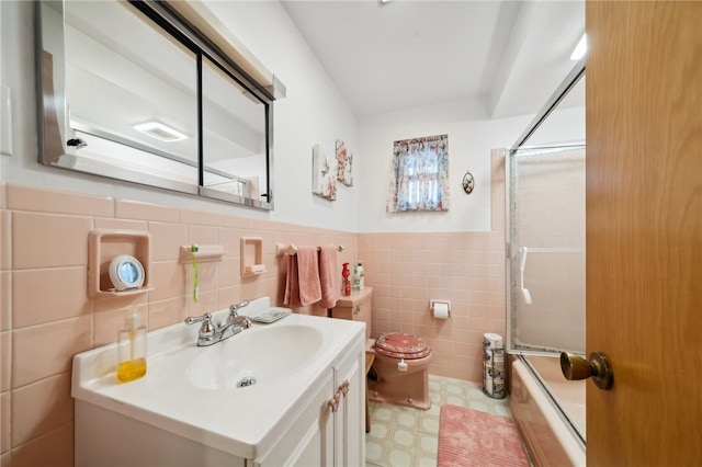 full bathroom with enclosed tub / shower combo, vanity, tile walls, and toilet