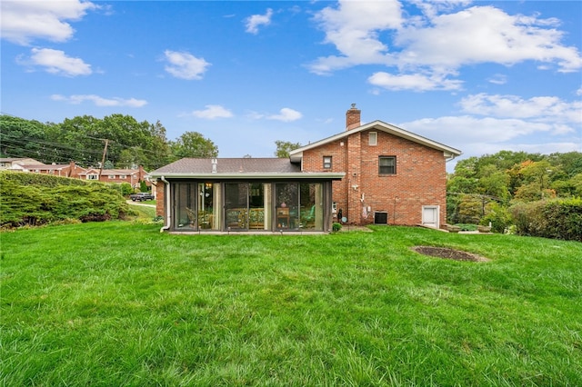 back of property with a yard and a sunroom