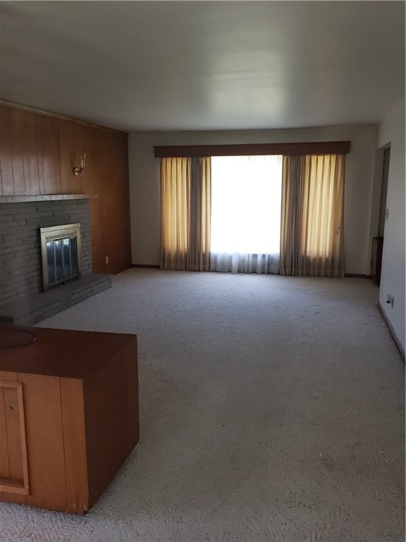 unfurnished living room with a brick fireplace and light carpet