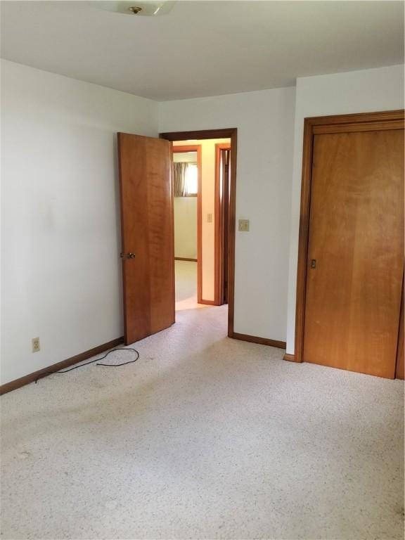 unfurnished room featuring light carpet and baseboards