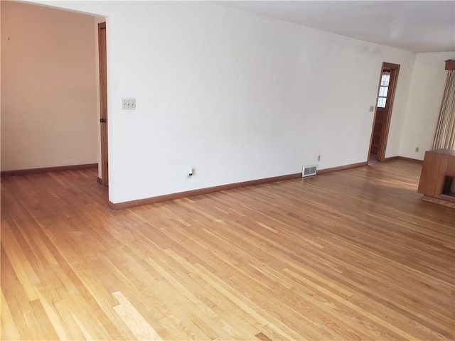 unfurnished room with visible vents, light wood-style flooring, and baseboards