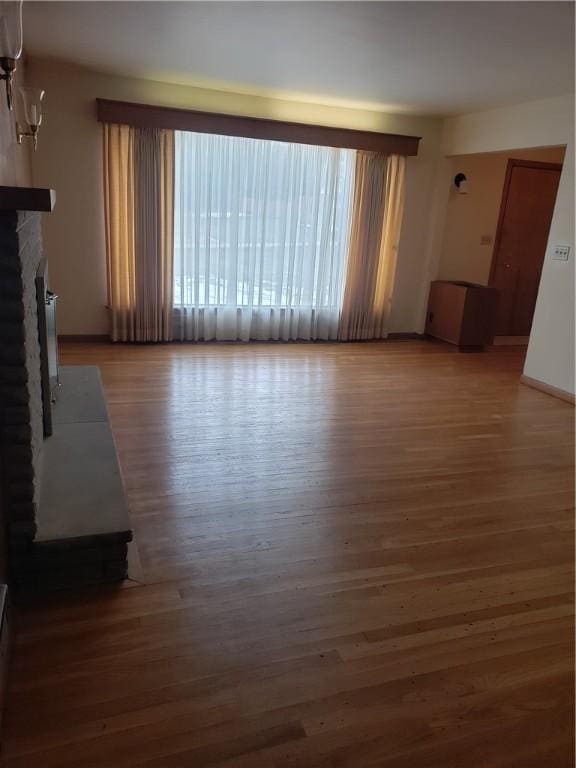 unfurnished living room featuring dark wood-style floors and a brick fireplace