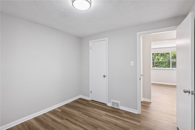 empty room featuring a textured ceiling and hardwood / wood-style flooring