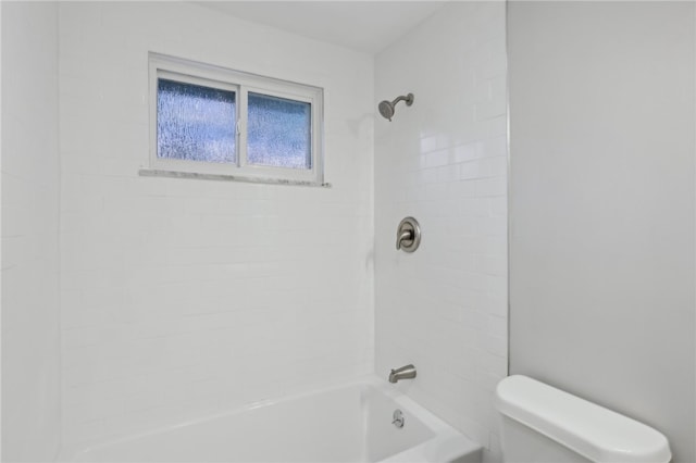 bathroom with tiled shower / bath combo and toilet