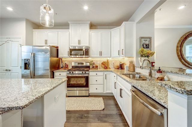 kitchen featuring light stone counters, white cabinets, pendant lighting, stainless steel appliances, and sink