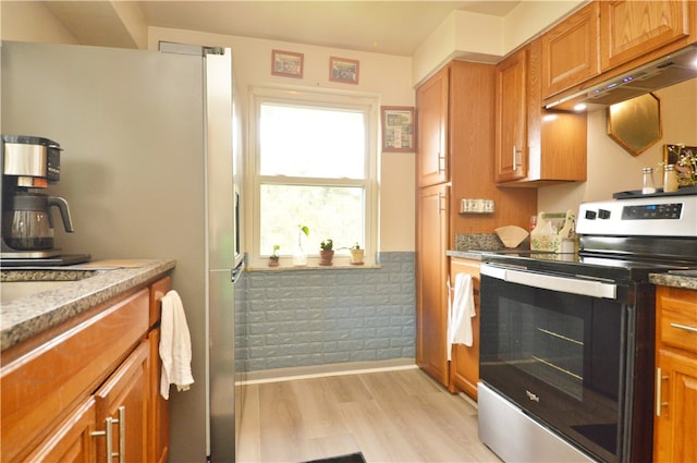 kitchen with appliances with stainless steel finishes, light hardwood / wood-style floors, custom range hood, and light stone countertops