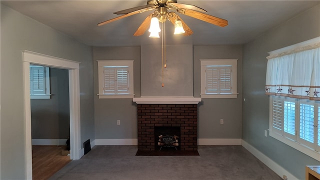 unfurnished living room with dark colored carpet, ceiling fan, and a brick fireplace