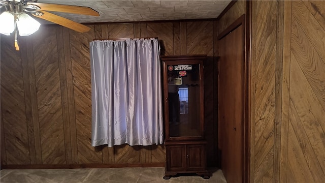 unfurnished room featuring wooden walls and ceiling fan