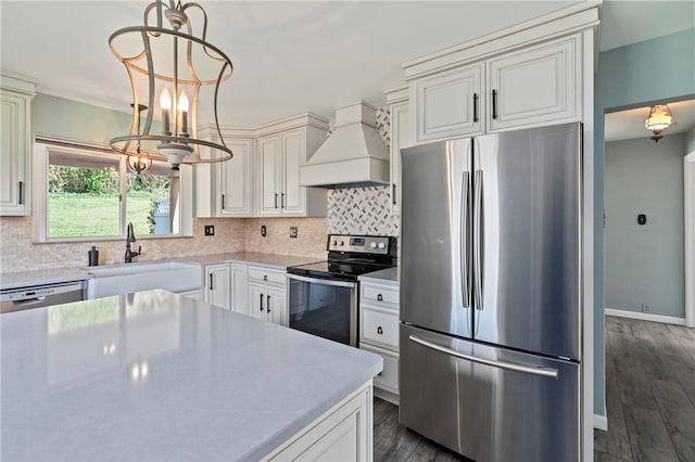 kitchen with sink, appliances with stainless steel finishes, dark hardwood / wood-style floors, custom range hood, and a notable chandelier