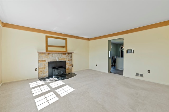 unfurnished living room featuring carpet flooring and a wood stove