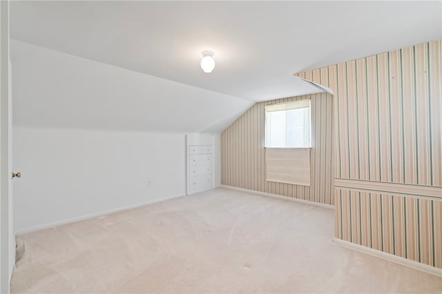 bonus room featuring lofted ceiling and light colored carpet