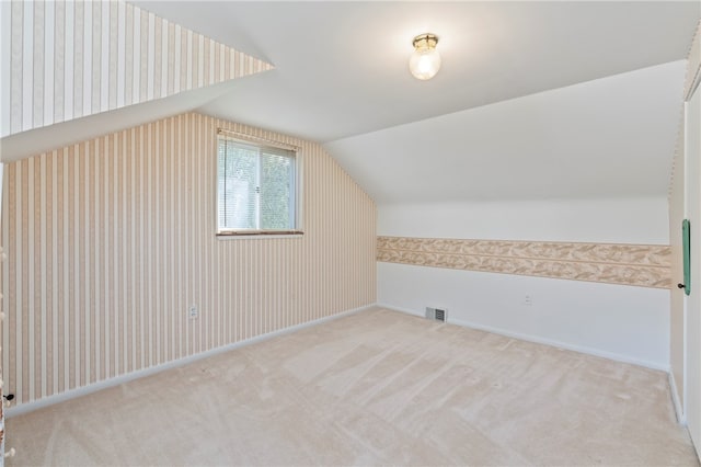 additional living space with light carpet and vaulted ceiling