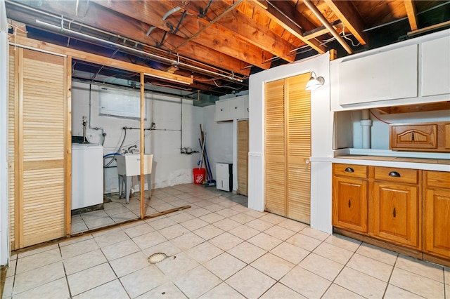 basement with washer / dryer, light tile patterned floors, and sink