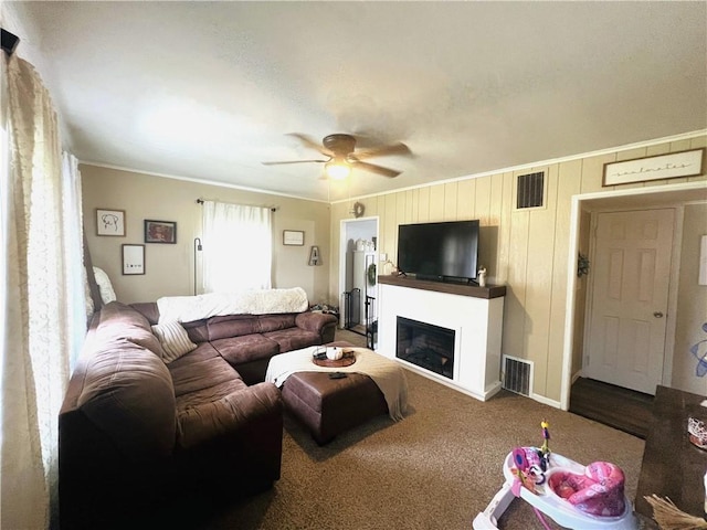 living room featuring carpet, ceiling fan, and crown molding