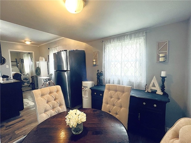 dining room featuring a healthy amount of sunlight, crown molding, and dark wood-type flooring