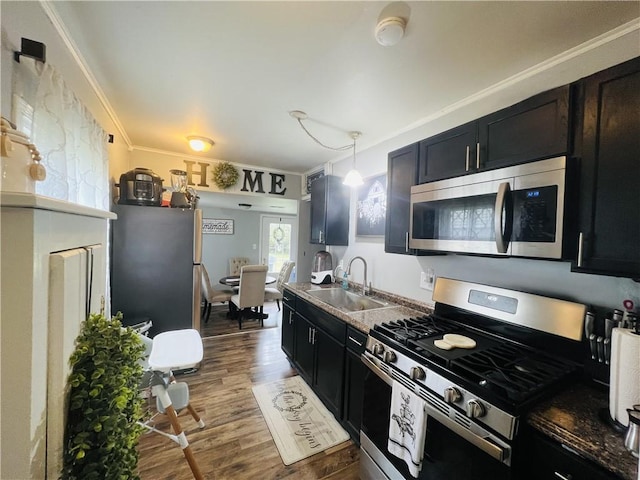 kitchen with sink, dark hardwood / wood-style flooring, decorative light fixtures, appliances with stainless steel finishes, and ornamental molding