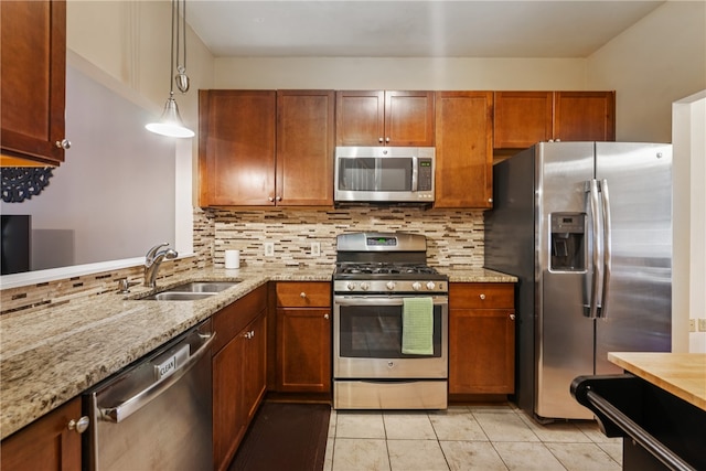 kitchen with appliances with stainless steel finishes, hanging light fixtures, tasteful backsplash, and sink