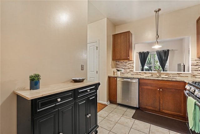 kitchen with appliances with stainless steel finishes, hanging light fixtures, tasteful backsplash, light tile patterned floors, and sink