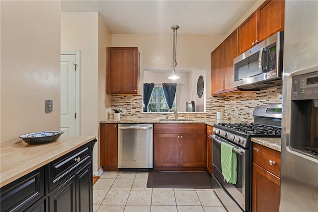 kitchen with sink, hanging light fixtures, decorative backsplash, appliances with stainless steel finishes, and light stone countertops