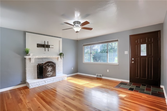 unfurnished living room with a fireplace, dark hardwood / wood-style flooring, and ceiling fan