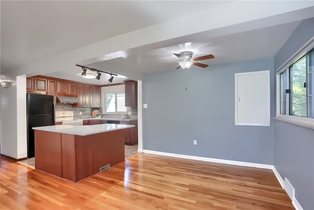 kitchen with range with electric stovetop, black fridge, a healthy amount of sunlight, and light hardwood / wood-style floors