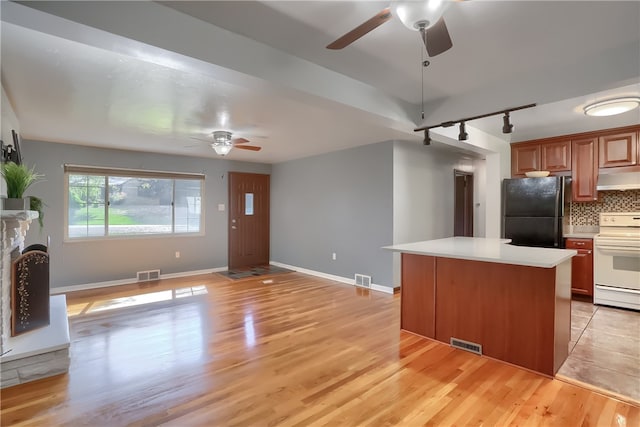 kitchen with black refrigerator, backsplash, light hardwood / wood-style floors, and white electric range oven