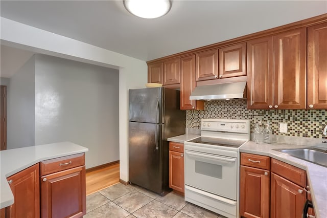 kitchen featuring electric range, sink, decorative backsplash, black refrigerator, and light tile patterned floors